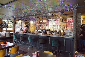 A bar area with a counter, stools, and a variety of bottles and glasses. - Cherry Bar Rooms (London)