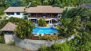 A large house with a swimming pool surrounded by lush greenery.