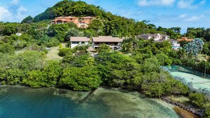 A coastal property with multiple houses, a tennis court, and lush greenery.