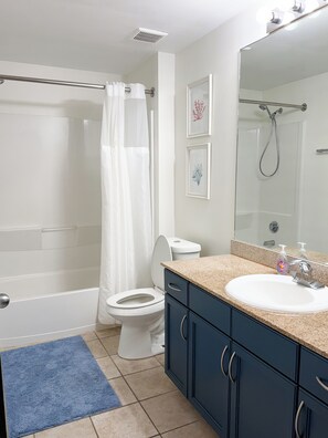 A bathroom with a shower, toilet, sink, and cabinet.