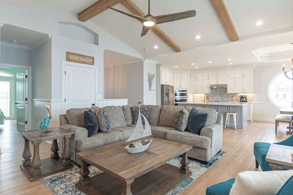 A spacious living room with a large sofa, a wooden coffee table, and a ceiling fan.