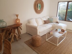 Ein gemütliches Wohnzimmer mit einem weißen Sofa, einem runden Spiegel und einem Couchtisch aus Holz.