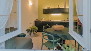 Una cucina compatta con una parete verde, un tavolo da pranzo con sedie e una finestra con tende.
