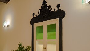 Una stanza con un tavolo verde, una pianta in vaso e un mobile decorativo nero con ante in vetro satinato.