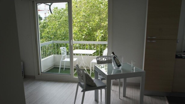 A balcony with a white table and chairs, a bottle, and a glass. - STUDIO DOWNTOWN LA BAULE (La Baule)