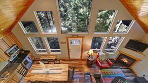 Ein geräumiges Loft mit großem Esstisch, einer gemütlichen Sitzecke mit Kamin und mehreren Dachfenstern für natürliches Licht.