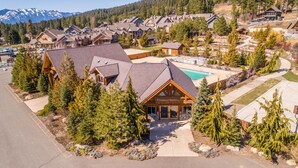 Ein großes Holzhaus mit Swimmingpool, umgeben von Bäumen und einer Bergkulisse.