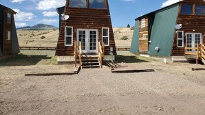 Une cabane en bois avec un porche à l’avant et une antenne parabolique.