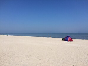 A beach with a tent and a few people in the distance.