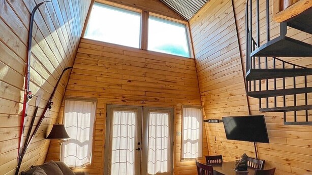 Ein gemütliches Blockhaus-Interieur mit Holzvertäfelung, einem Essbereich, einer Couch und einer Treppe.