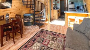 Ein gemütliches Blockhaus-Interieur mit Holzvertäfelung, einer Wendeltreppe, einem Essbereich und einer Küche.