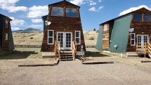 Een rustieke hut met een steil dak, een veranda en een schotelantenne.
