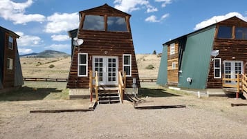 Une cabane rustique avec un toit à forte pente, une véranda et une antenne parabolique.