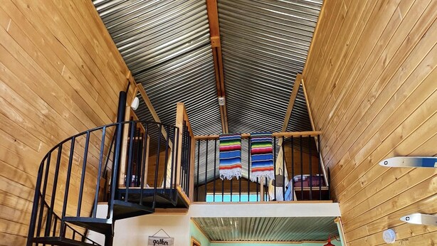 Een houten interieur met een spiltrap, een keukenhoek en een gezellige zithoek.