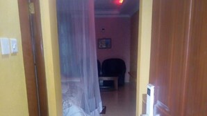A narrow hallway with a bed and a chair in the background. - Le Grand Hotel Oyugis (Oyugis)