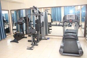 Una palestra con attrezzature per esercizi, tra cui tapis roulant, macchinari per pesi e una parete con specchi.