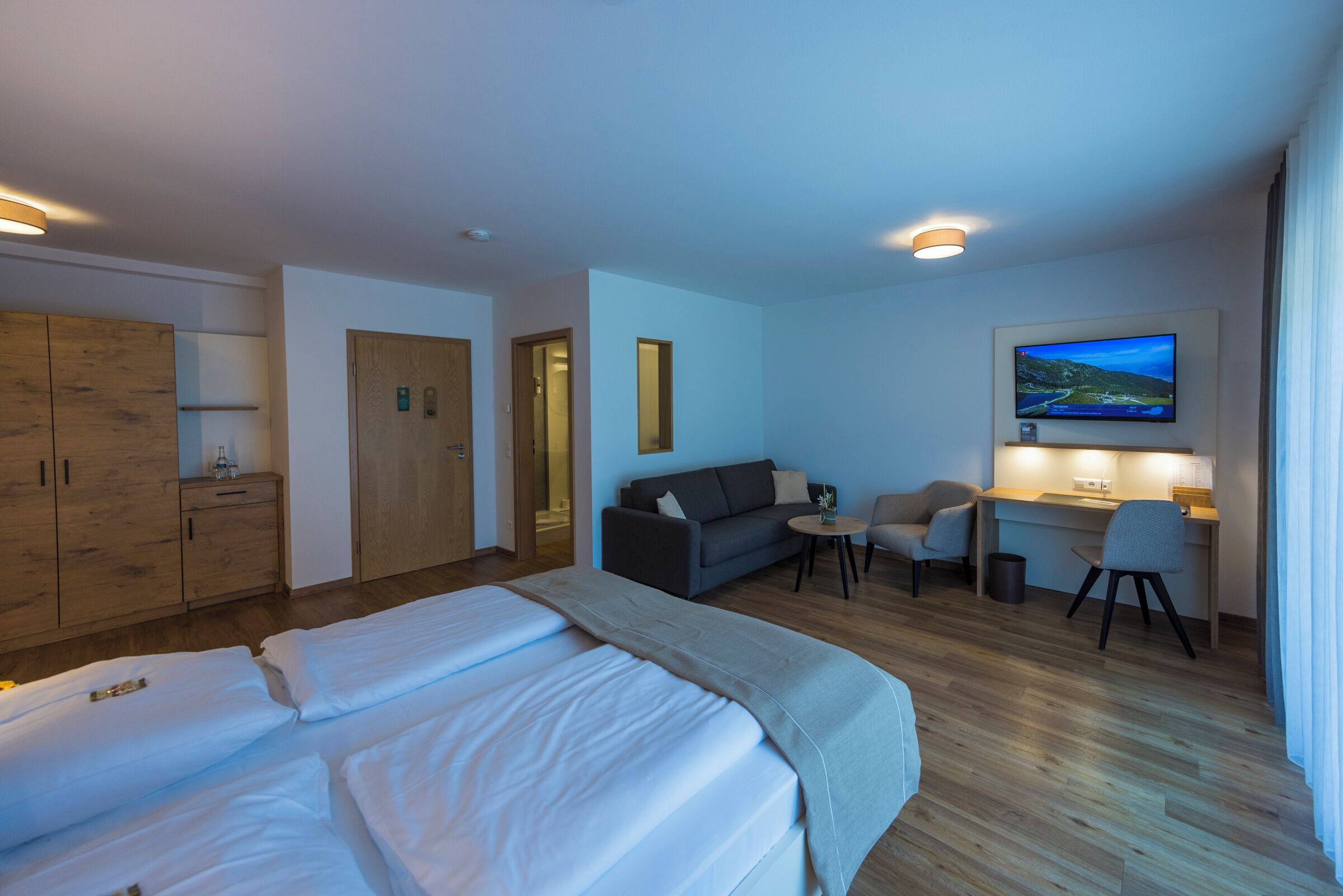 Una habitación de hotel con cama, sofá, escritorio y televisión.