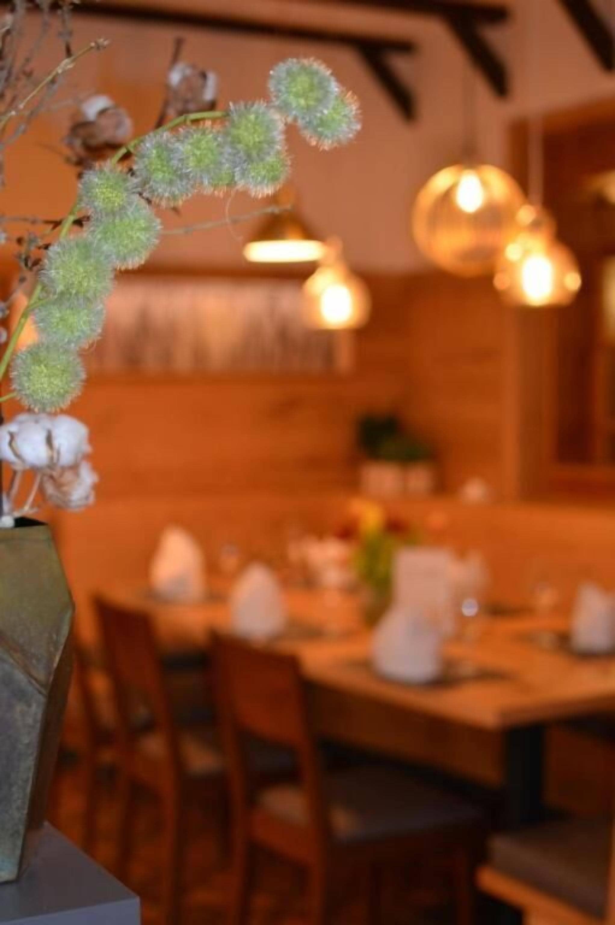 Un comedor con una mesa lista para dos personas, un jarrón con flores secas e iluminación ambiental cálida.
