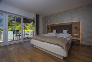 Un dormitorio con una cama grande, cabecera de madera, mesita de noche y puerta corrediza de vidrio que da a un espacio exterior con una mesa y sillas.