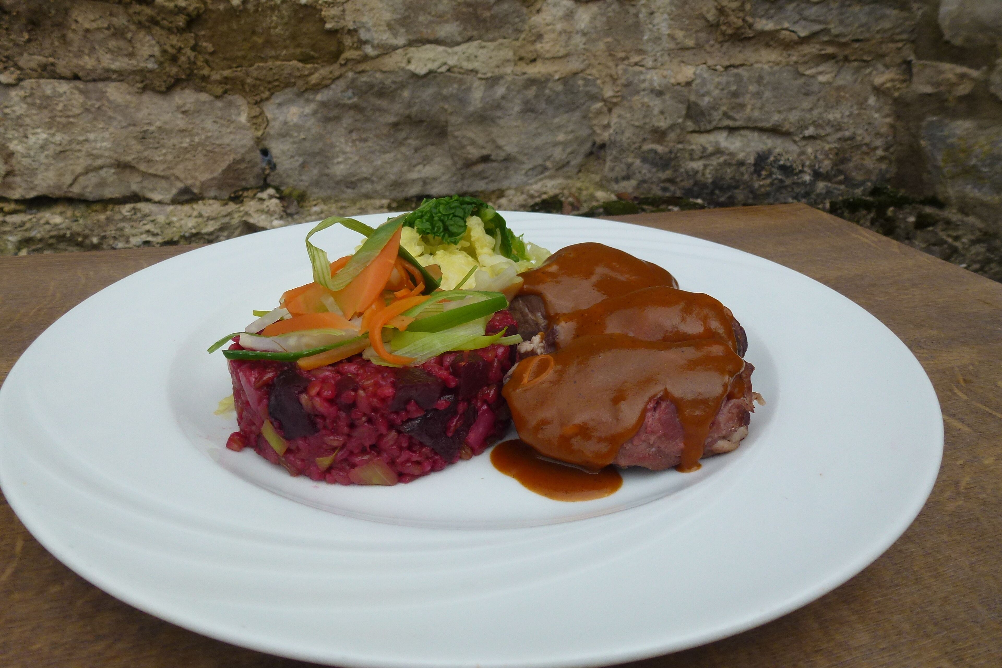 Un plato de comida con un guiso de carne, col roja y una mezcla de verduras.