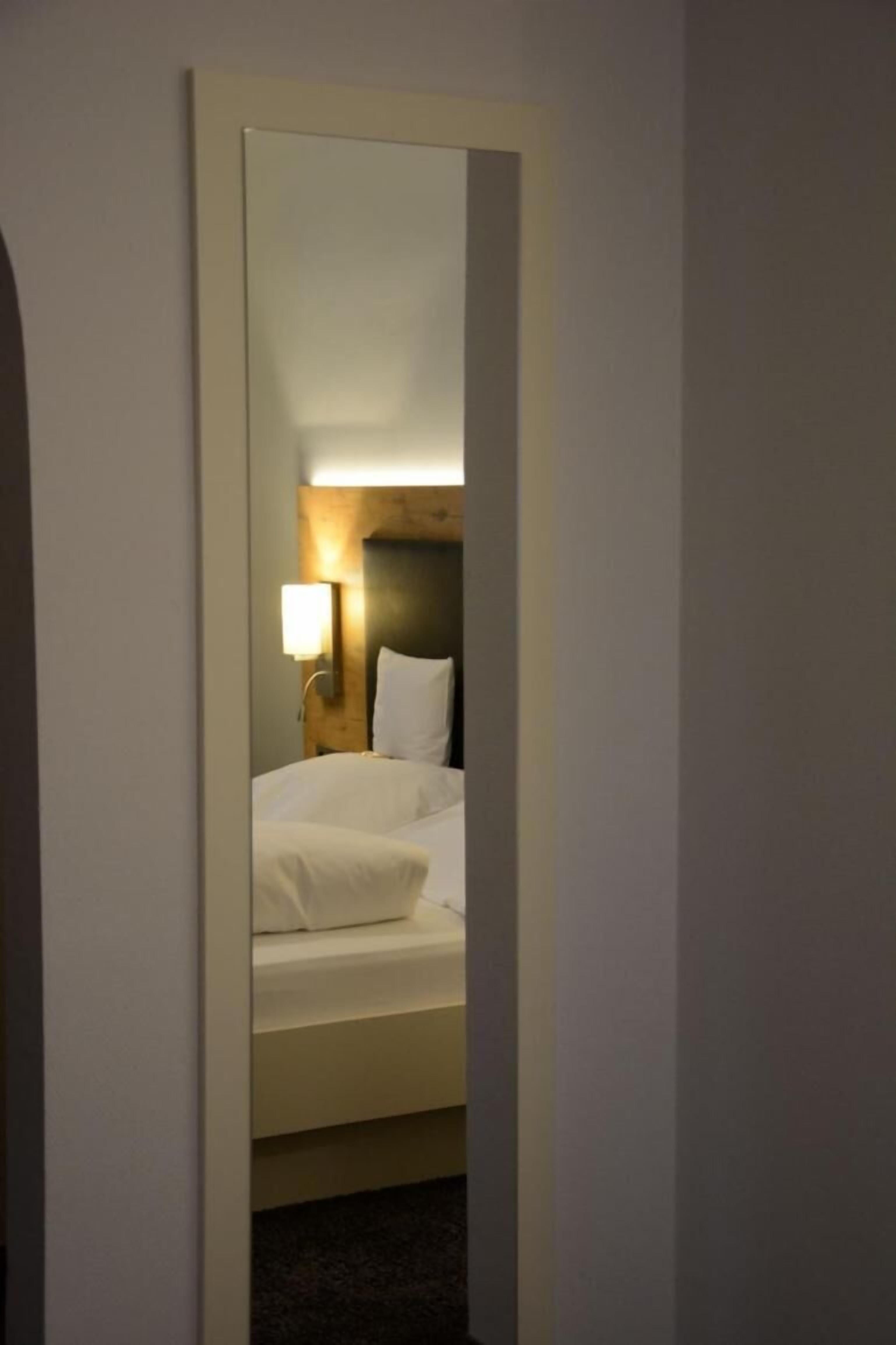 A hotel room with a bed, a nightstand with a lamp, and a headboard.
