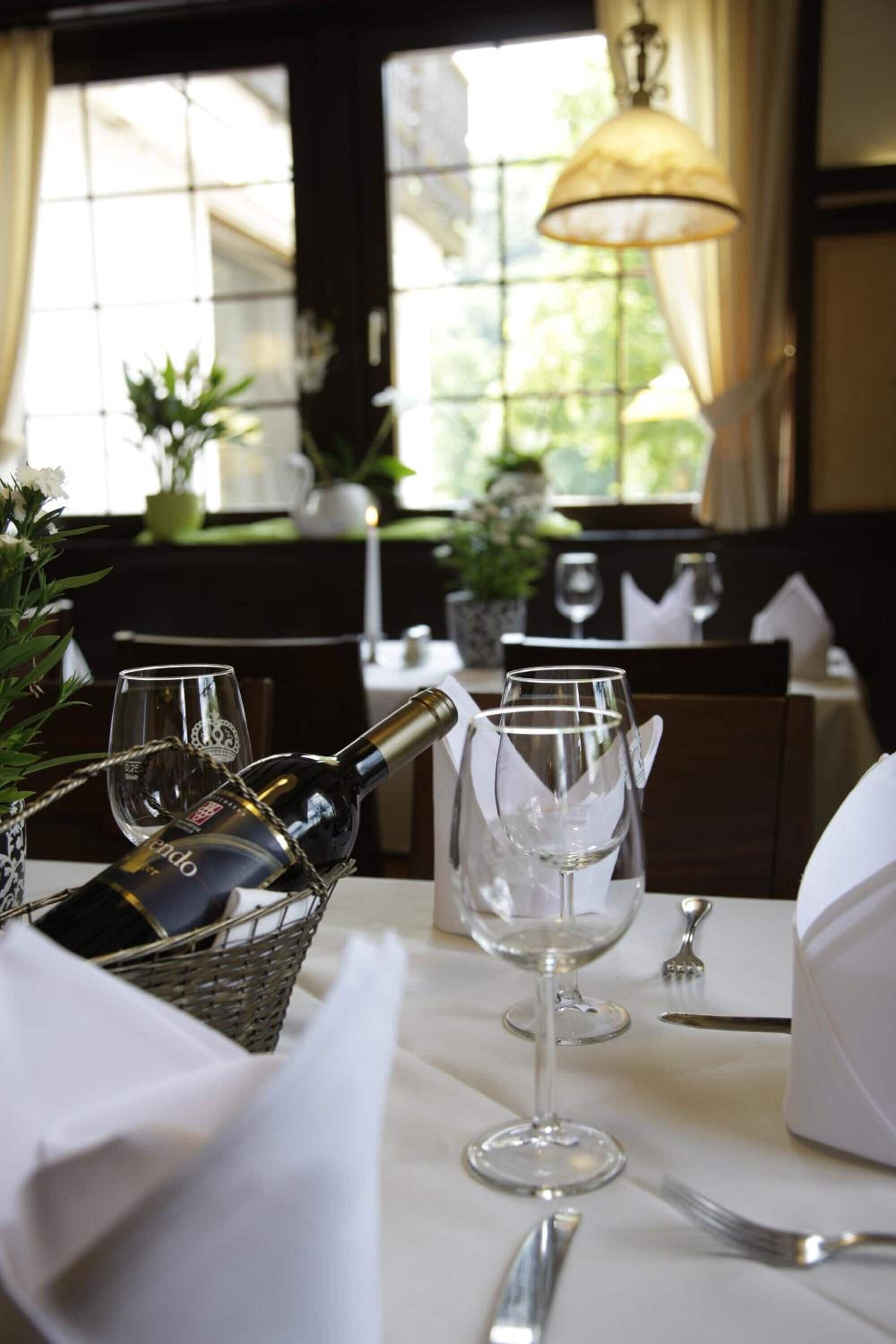 A dining table set with a bottle of wine, two wine glasses, a basket, and a candle.
