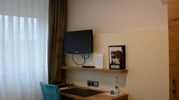 Ein Hotelzimmer mit Schreibtisch, Stuhl, Fernseher und einem Bett.
