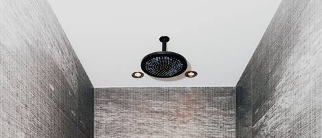 Een douche met gestructureerde wanden, een handdouche en twee kleine schermen die natuurscènes tonen.
