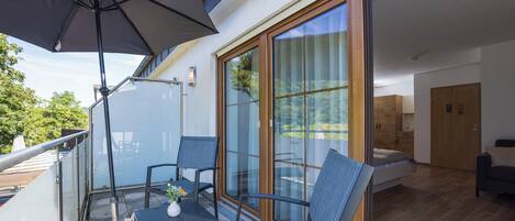 A balcony with a table, chairs, and a large umbrella.