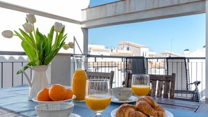 A table with breakfast items including oranges, croissants, and orange juice, set on a balcony with a view of buildings. - Lovely apartment WiFi, A/A, Parking, bike station, terrace & pool (Altea)