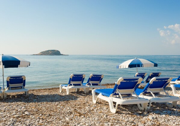 Ranta lähistöllä, aurinkotuoleja, rantapyyhkeitä