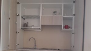 A compact kitchen with a sink, cabinets, and a small table with a chair. - Affittacamere Stazione Empoli (Empoli)