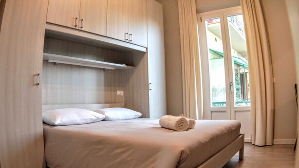A bedroom with a bed, a wardrobe, and a view of the outside. - Affittacamere Stazione Empoli (Empoli)