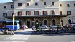 A building with a clock on the facade, a covered entrance, and bicycles parked in front. - Affittacamere Stazione Empoli (Empoli)