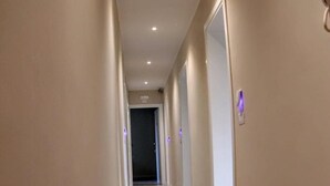 A hallway with a wooden floor, beige walls, and recessed lighting. - Affittacamere Stazione Empoli (Empoli)