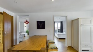 A modern interior with a wooden dining table, a bed with a view, and a white wardrobe. - Fantastic central Zugspitze view with parking lot  (Garmisch-Partenkirchen)
