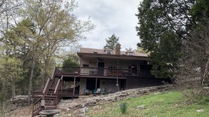 A two-story building with a balcony, a stone staircase, and outdoor seating.