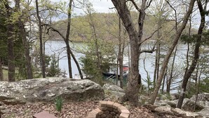 A wooden bench, a stone fire pit, and a lake with a dock in the background.