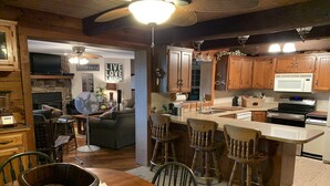 A cozy kitchen with wooden cabinets, a central island with bar stools, and a dining table with chairs.
