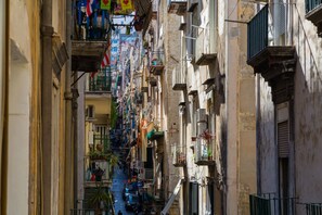 A narrow street lined with multi-story buildings, balconies, and potted plants. - Residenza Toledo by Wonderful Italy (Napoli)