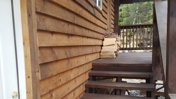 A wooden cabin with a set of wooden stairs leading to a deck.