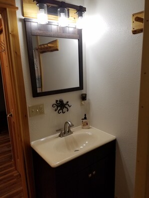 Un baño con lavamanos blanco, un espejo y una lámpara sobre él.