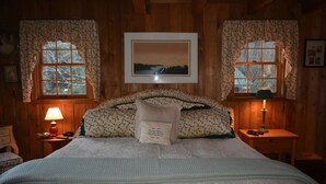 Ein gemütliches Schlafzimmer mit einem großen Bett, floralem Bettzeug, zwei Nachttischlampen und einem gerahmten Bild an der Wand.