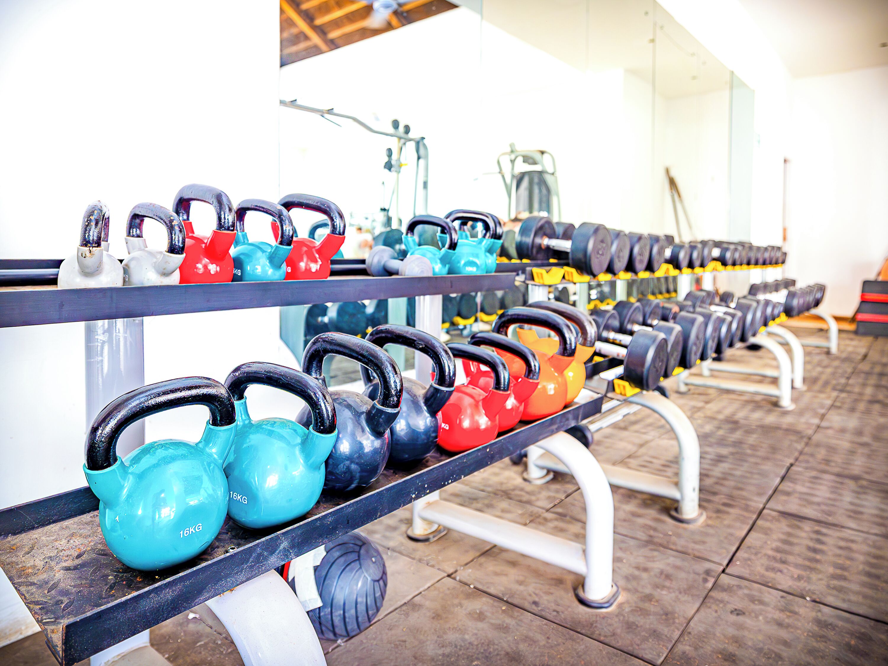 Kettlebells and dumbbells arranged on racks in a gym.