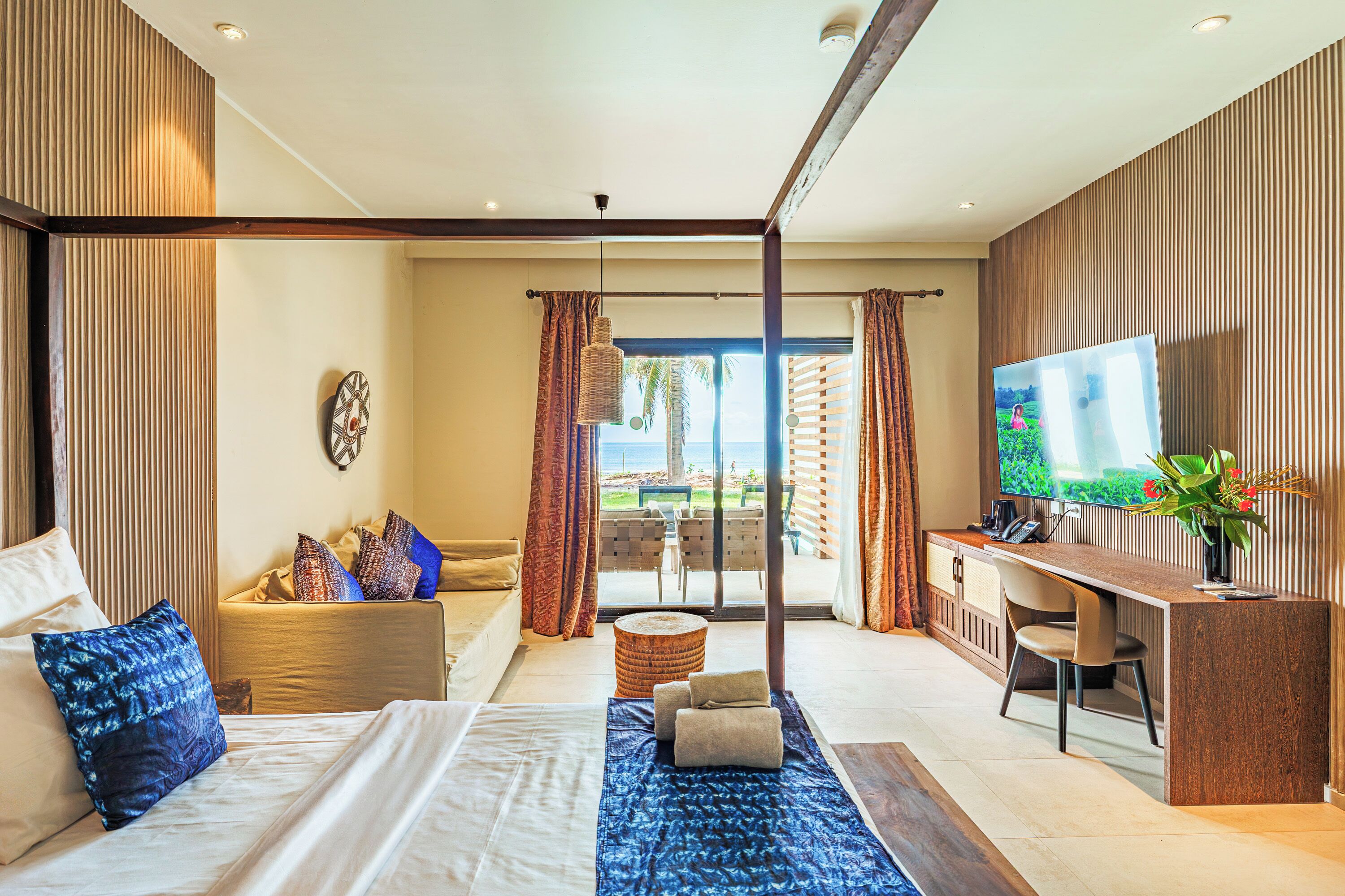 Una habitación de hotel moderna con una cama, un escritorio, un televisor y vistas al exterior.