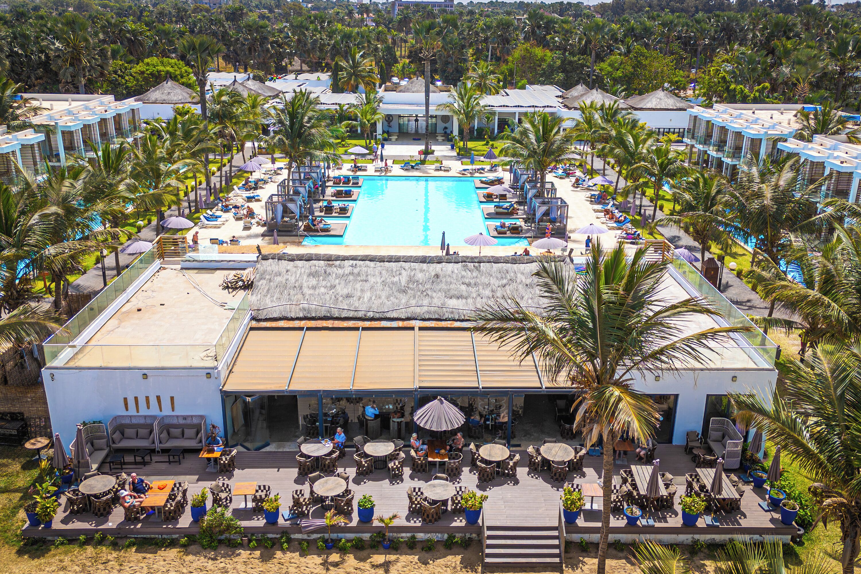 A resort with a central swimming pool, outdoor seating areas, and multiple guest rooms.