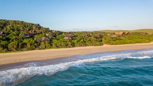 A coastal area with beachfront houses, sandy beach, and ocean waves.