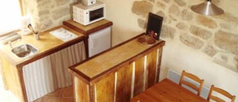 A compact kitchen with a stone wall, a wooden table, and a sink.