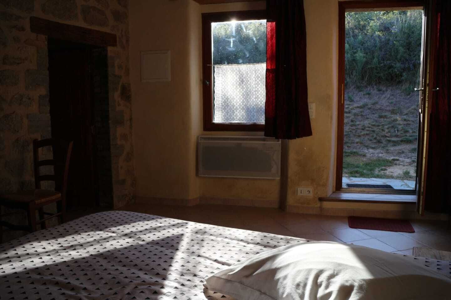 Een kamer met een bed, een raam met uitzicht op de omgeving en een radiator.
