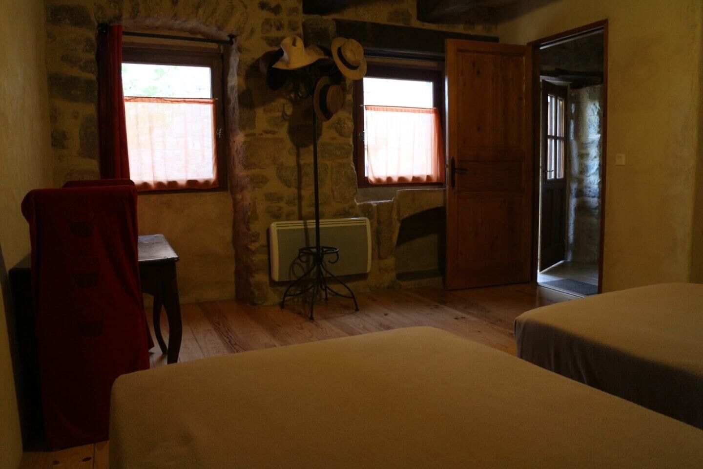 Een kamer met twee bedden, een radiator, een hoedenrek en een houten deur.